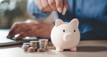 Hand putting a coin in a piggy-bank 
